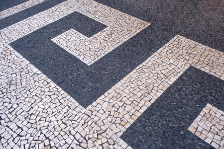 Traditional design on cobblestone sidewalk, Funchal, Madeira island, Portugal. Black and white mosaic floor from calcada tiling.の写真素材