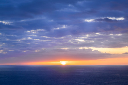 The sun shines through the clouds over the ocean. Beautiful, bright, colorful sunset. Summer time and mood. Beautiful vibrant evening.の写真素材