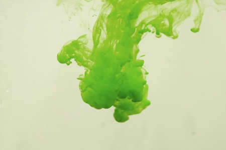 Colors dropped into liquid in motion. Ink swirling in water. Green ink in water, abstract backgroundの写真素材