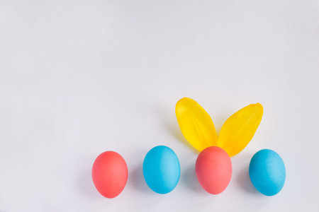 Happy Easter Concept. Big Colorful Eggs with Furry Bunny Ears isolated on white background. Top view...