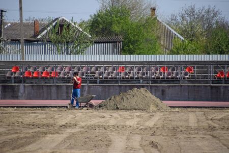 Slavyansk-on-Kuban, Russia - April 25, 2019: Repair work at the stadium. Delivery and leveling of sand.のeditorial素材