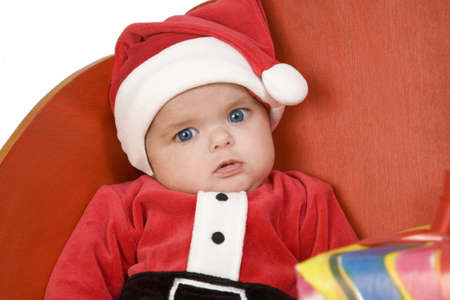 A baby dressed as Santa Claus sitting in a sleighの写真素材