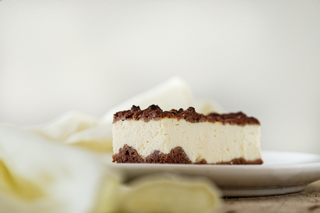 Slice of cheesecake with chocolate shortcrust pastry and chocolate crumble. Wooden background. Horizontal. Light food photography. Free text space.の写真素材