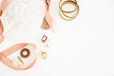Flat lay for fashion blog and social media. Woman's glamour golden beauty accessories on a white background. Lingerie, jewelry, perfumes, spiral hair ties and hair clips. Copy space for text. Horizontalの写真素材