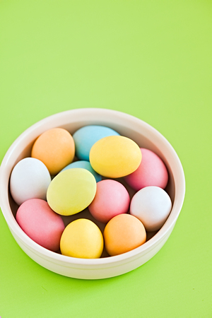 Colorful decorated eggs on a white plate and greenery background. Easter card. Negative spaceの写真素材