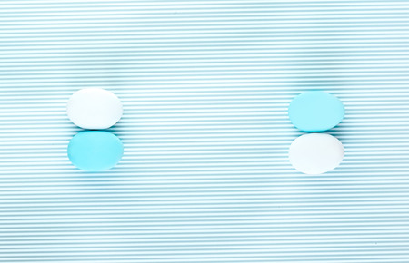 Pair of white and light blue eggs on a colorful striped backdrop. Creative design, minimal concept. Negative spaceの写真素材