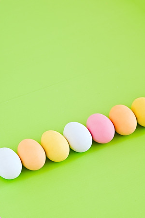 Diagonal row of colorful decorated eggs on a greenery background.  Pastel colors. Easter card. Negative spaceの写真素材