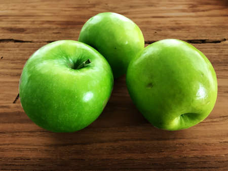 Three green apples on a wood surfaceの写真素材