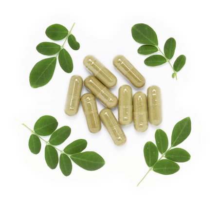 Moringa oleifera capsule with green fresh leaves on white backgroundの写真素材