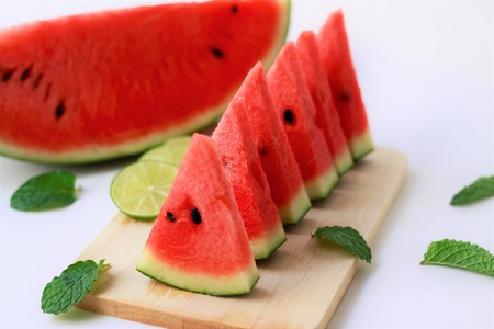 Watermelon and sliced to pieces of watermelon on a wooden plate, dessert, fruits, summer,on a white backgroundの写真素材