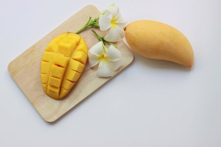 Fresh yellow mango and mango cubes on wooden dish on white background, Top view, Copy spaceの写真素材