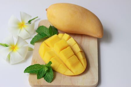 Tropical fruits with yellow mango and mango cubes on  wooden plate on white background, Healthy food, Fresh vitaminsの写真素材