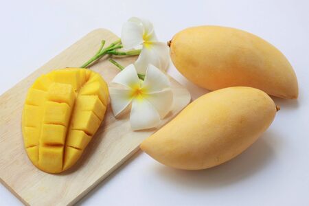 Tropical fruits, yellow mangoes and mango cubes on  wooden plate on white backgroundの写真素材