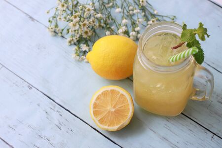 Lemonade with ice cubes and mint in a glass jar and lemons on wooden background, Refreshing Summer Drinksの写真素材