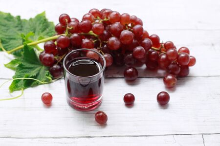 Glass of grape juice with bunch of fresh red grape fruits on wooden background, Fresh vitamins, Healthy and detox  foodの写真素材