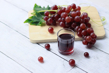 Homemade fresh grape juice in glass drink with red grape fruits on wooden plate on  wooden...