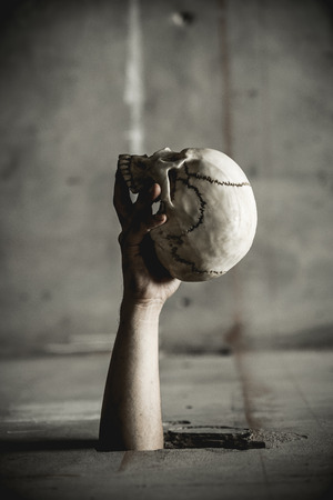 Skulls were held with the right hand of the man that emerges from the wall. Halloween Day element.の写真素材