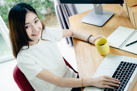 Young asian girl is freelancer with her private business at home office, working with laptop, coffee, online marketing, Customer order and packaging or packing.の写真素材