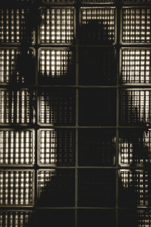 A witch or zombie girl's standing behine the glass opaque costumes on Halloween. The silhouette photo.の写真素材