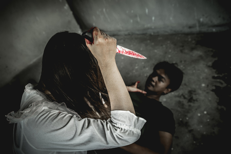 Asian girl dress killer to Halloween festival She's holding a kitchen knife big soaked in blood with scary eyes ready to kill a man in front of her.の写真素材