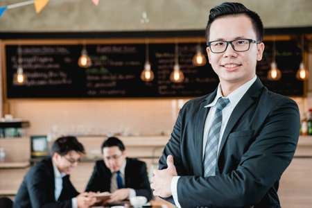 Business man wearing a suit, holding a helmet in front of a coffee shop.