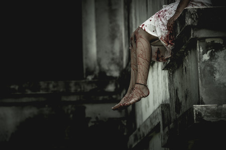 Zombie woman sitting on the edge of the window in an abandoned building on Halloween. Women dressed in zombieの写真素材