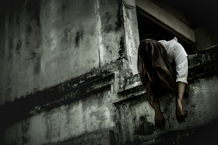 Zombie woman lying dead on the edge of my window in an abandoned building on Halloween. Women dressed in zombieの写真素材