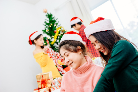 Groups of friends are Asian men and women decorated the Christmas tree. To celebrate the Christmas season. They drink wine and champagne to enjoy together happily.の写真素材