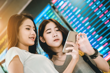 Asian teenage girl is using a smartphone to check flight at the international airport to travel on weekends.の写真素材