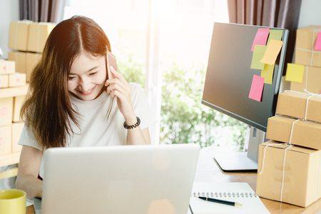 Young asian girl is freelancer with her private business at home office, working with laptop, coffee, online marketing, Customer order and packaging or packing.の写真素材