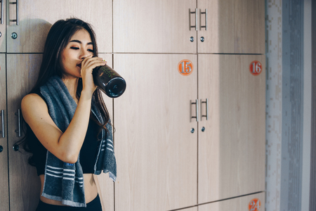 Asian woman exercising in the gym, Young woman workout in fitness for her healthy and office girl lifestyle. she is drinking a protein shake.の写真素材