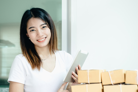 Young asian girl is freelancer with her private business at home office, working with laptop, coffee, online marketing, Customer order and packaging or packing.の写真素材