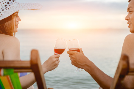 Asian couple walking on the beach when the sun is about to sunset during the honeymoon. There are  Couple walking on Valentine's Day and drinking the wine.の写真素材