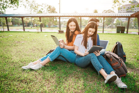A group of young or teen asian student in university smiling and reading the book and look at the...