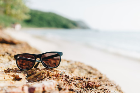 A sun glass put on the rock at the beach in sunny day of vacation time.の写真素材