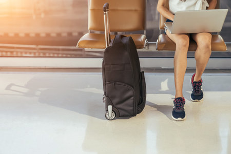 Asian teenage girl is using a laptop to check email or social network or internet at the international airport to travel on weekends.の写真素材