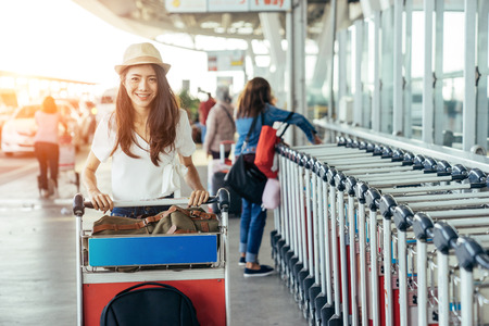 Asian teenage girl is using a smartphone to check flight at the international airport to travel on weekends. Teenage girl in airport.の写真素材