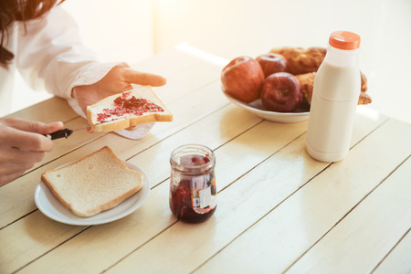 Asian girl who just wake up in the morning as relaxed. She was put down the jam on bread.の写真素材