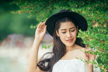 Asian girl wearing a long white dress walking or standing at the beach on vacation weekend. Single lady sitting at the beach by alone. Girl with white dress on the beach.の写真素材