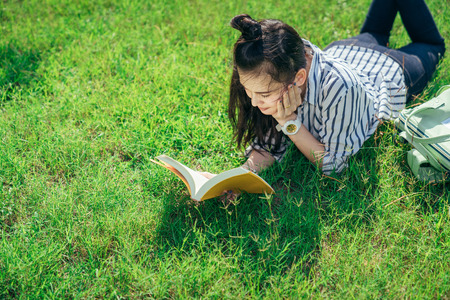A group of teenage student in university smiling and reading the book in summer holiday.の販売画像