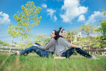 A group of teenage student in university smiling and reading the book in summer holiday. They listening music while reading the books together.の写真素材