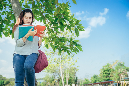 A group of teenage student in university smiling and reading the book in summer holiday.の写真素材