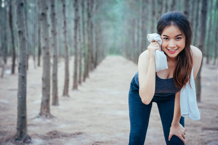 Asian girl is exercising at the weekend in a pine forest green and lush beautiful. Sport girl and...