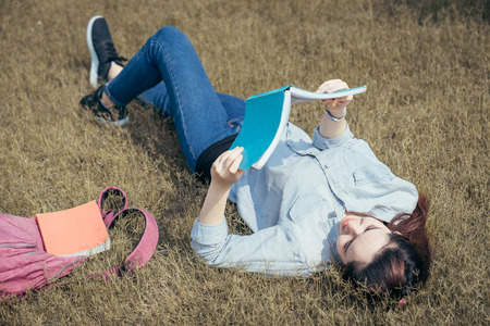 A group of teenage student in university smiling and reading the book in summer holiday.の写真素材