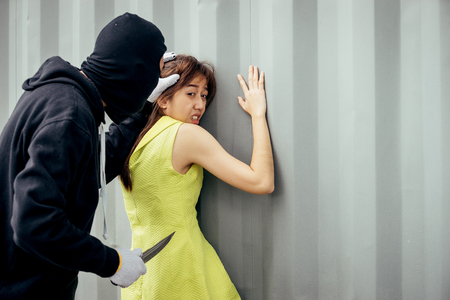 Man hat bandit black robber was carrying a knife, threatening to rob a woman of her property.の写真素材