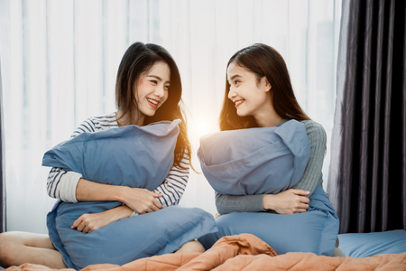 Asian woman young Lesbian couple is hugging the pillow together in their indoor house on Vanlentine's Day.の写真素材