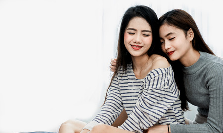 Asian woman young Lesbian couple is hugging the pillow together in their indoor house on Vanlentine's Day.の写真素材