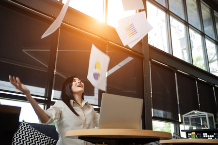 An Asian girl is freelancer woman, she is working by using the laptop computer and drinking a cup of coffee on morning in a coffee shop or her office.の写真素材