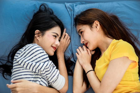 A top view photo close up to couple asian woman are lesbian sleeping ont the blue bed. Couple concept, Lesbian Couple concept. Sex LGBT and lifestyle concept.の写真素材