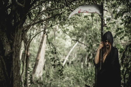 Asian woman dress black as Grim Reaper of death and holding or wielding a large scythe in Halloween...